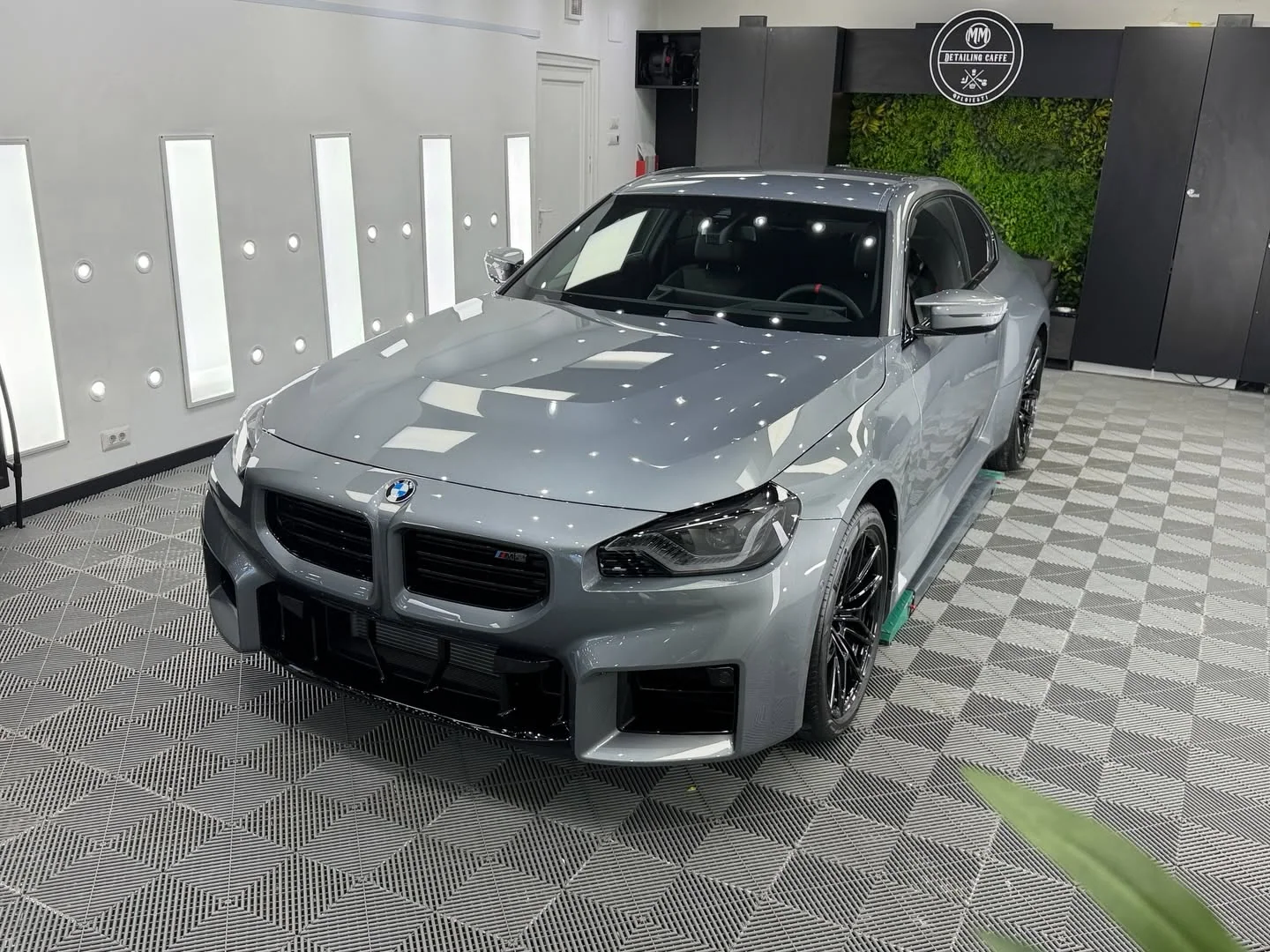 BMW M2 gri fotografiat frontal în atelier