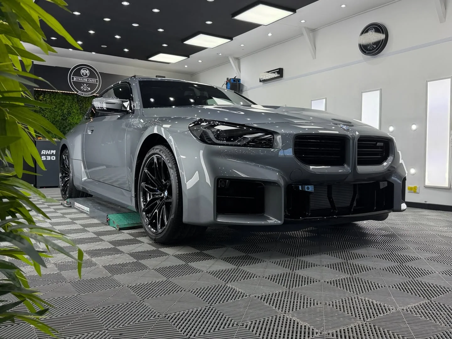 BMW M2 gri fotografiat din față de la nivelul solului