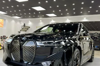 BMW iX negru fotografiat în atelierul de detailing